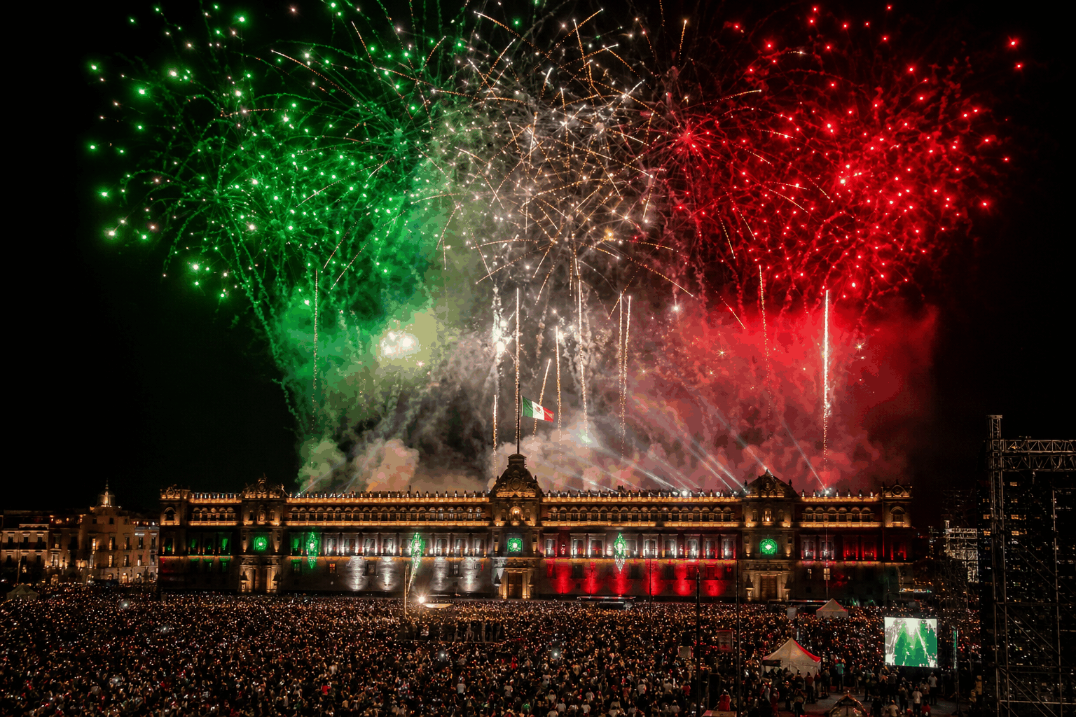 Tricolour green, white and red fireworks over a floodlit government palace and crowd during Mexico's Independence Day (El Grito)