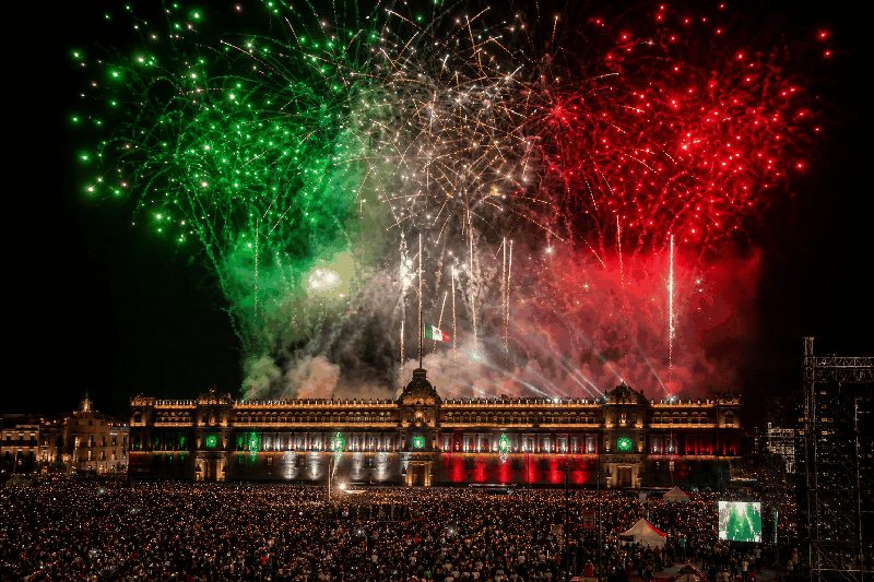 Green, white and red fireworks — the colours of the Mexican flag — bursting over a floodlit colonial government palace and a huge crowd during Mexico's Independence Day (El Grito) celebration